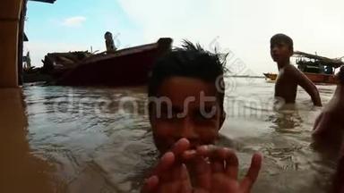 在瓦拉纳西码头淹没恒河的背景船上，另一个孩子在混乱的水面上飞溅